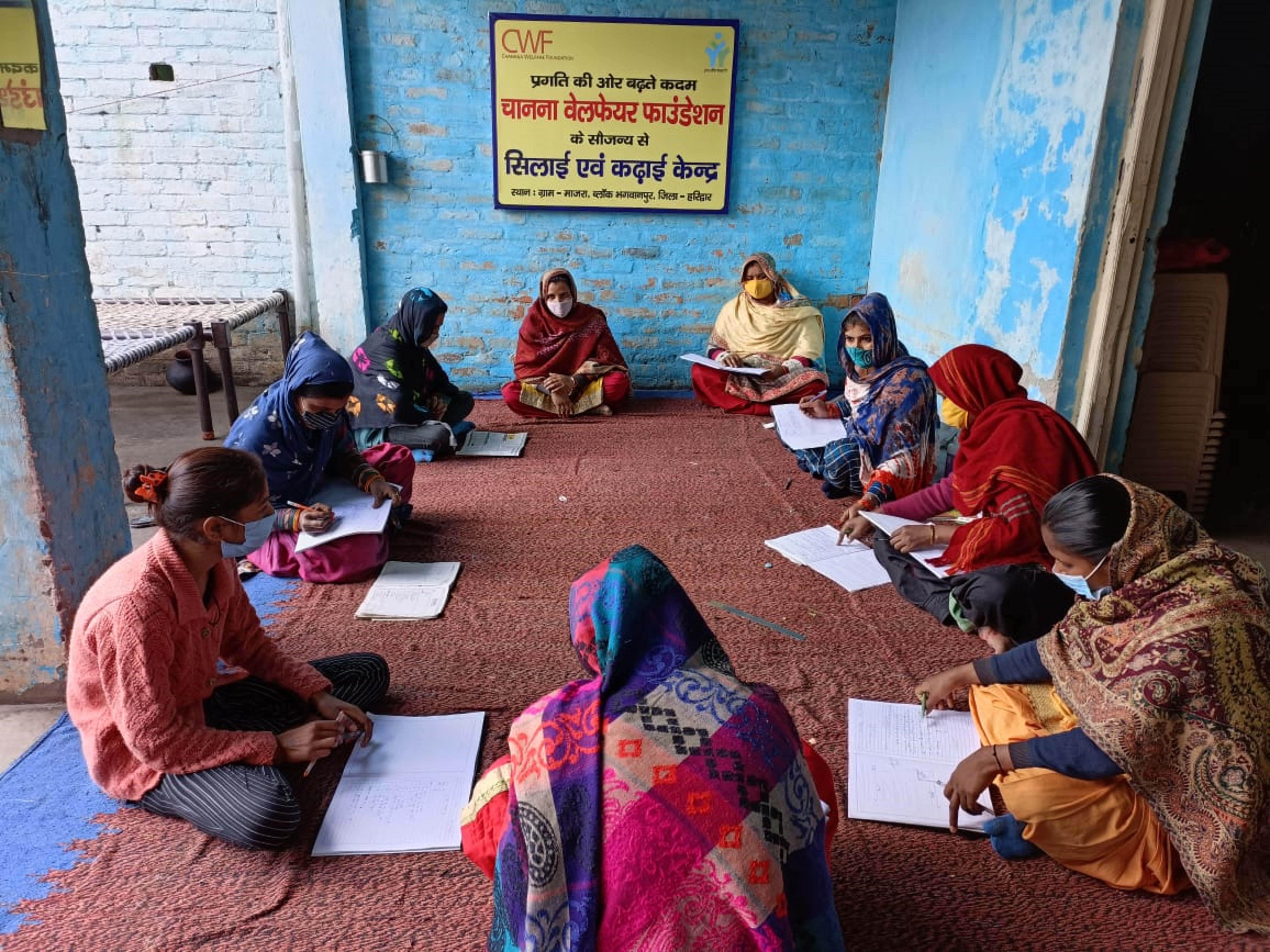 Girls and women are writing the theory of Tailoring at Tailoring and Embroidery centre, Majra
